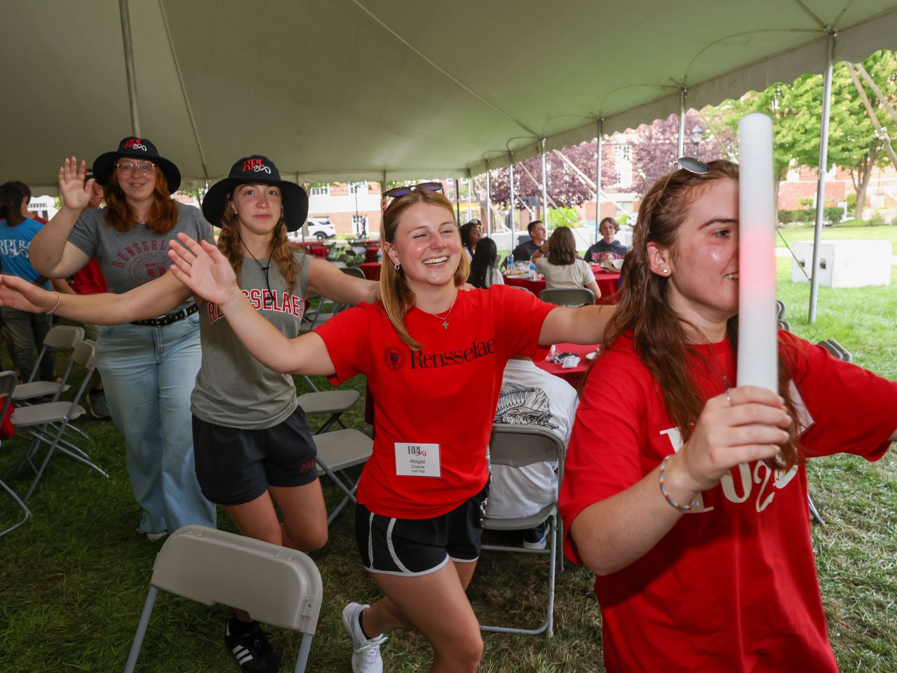 Four students dancing in a line under a big tent