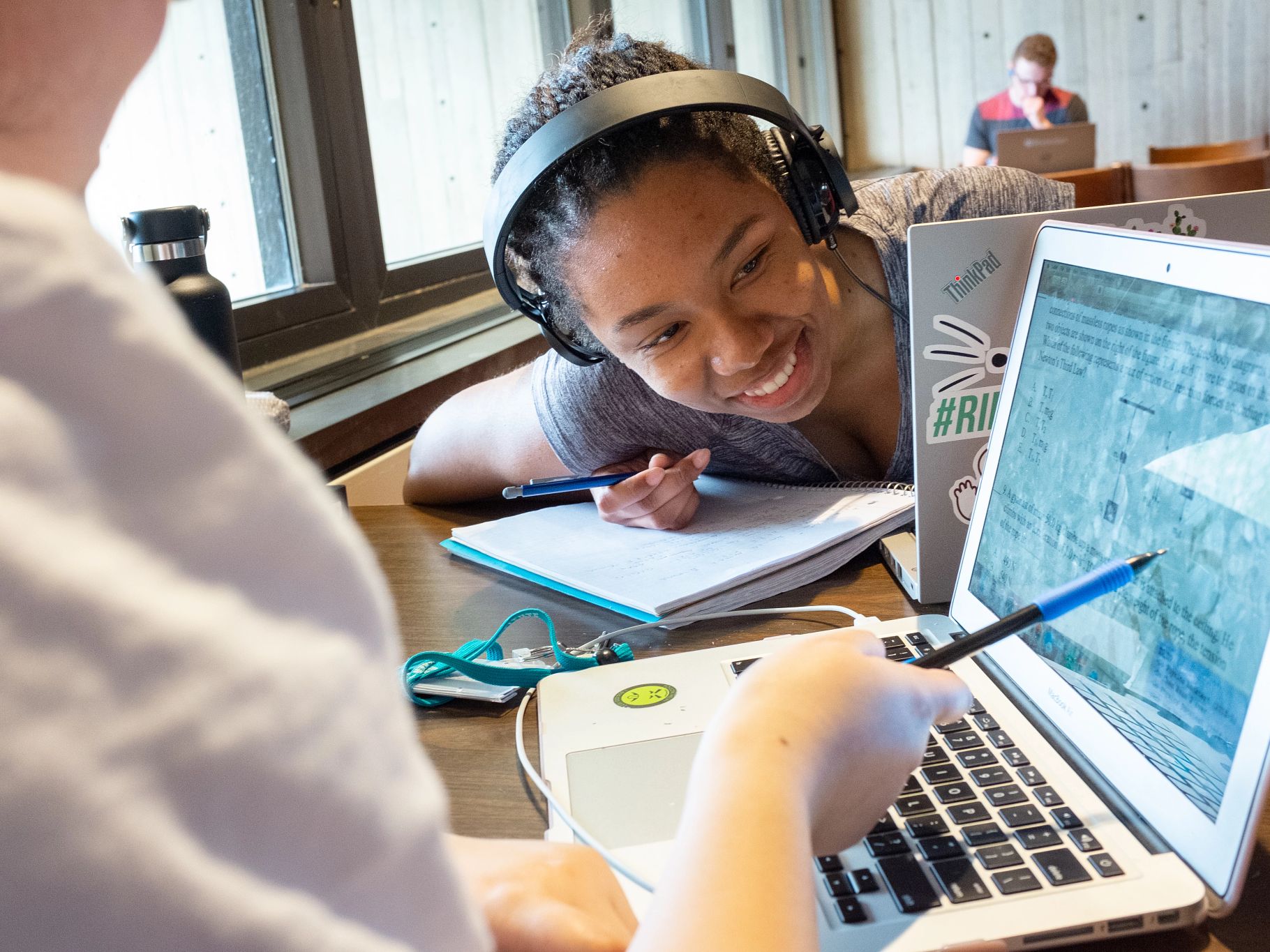 Student looks at another student's laptop