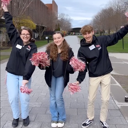 Three students with red and white pom poms