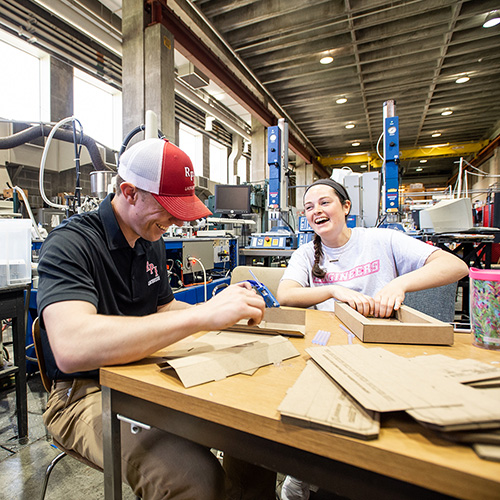 Students working at a table building models out of cardboard